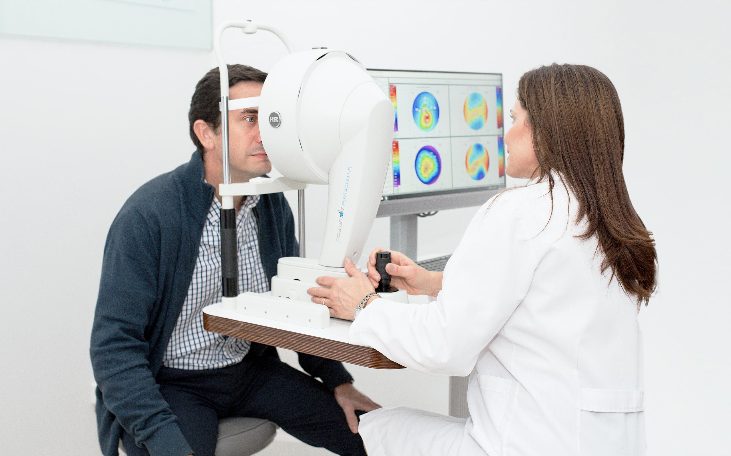 Un hombre se somete a un examen ocular con un especialista que utiliza un equipo de diagnóstico avanzado en un entorno clínico.